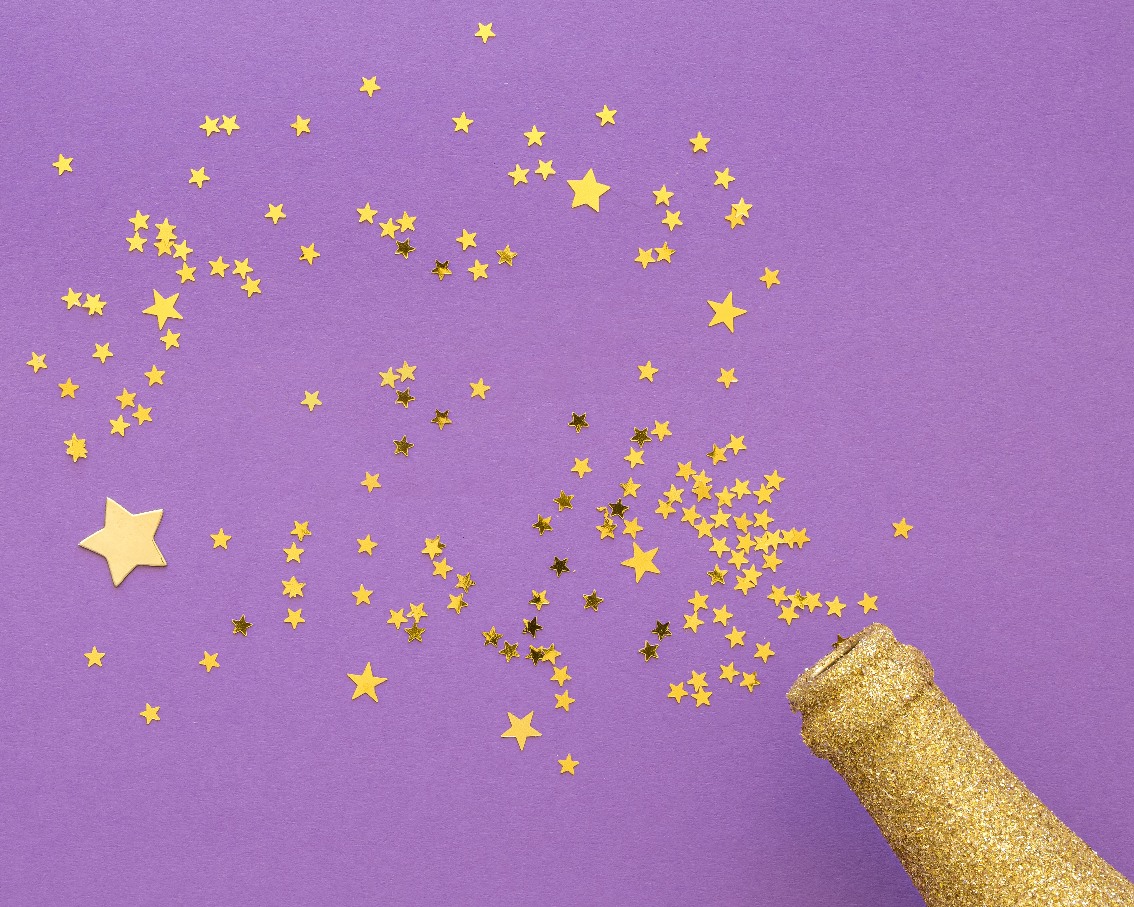 Auf einem lila Hintergrund ist eine goldene Flasche mit goldenem Stern-Konfetti zu sehen.