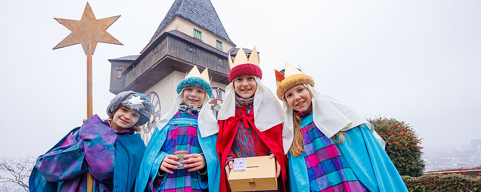 Die heiligen drei Könige samt Sternsinger schauen in die Kamera.
