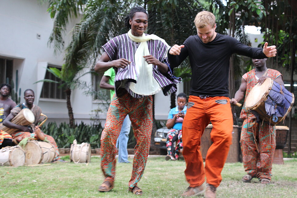 Männer in Ghana tanzen und trommeln.
