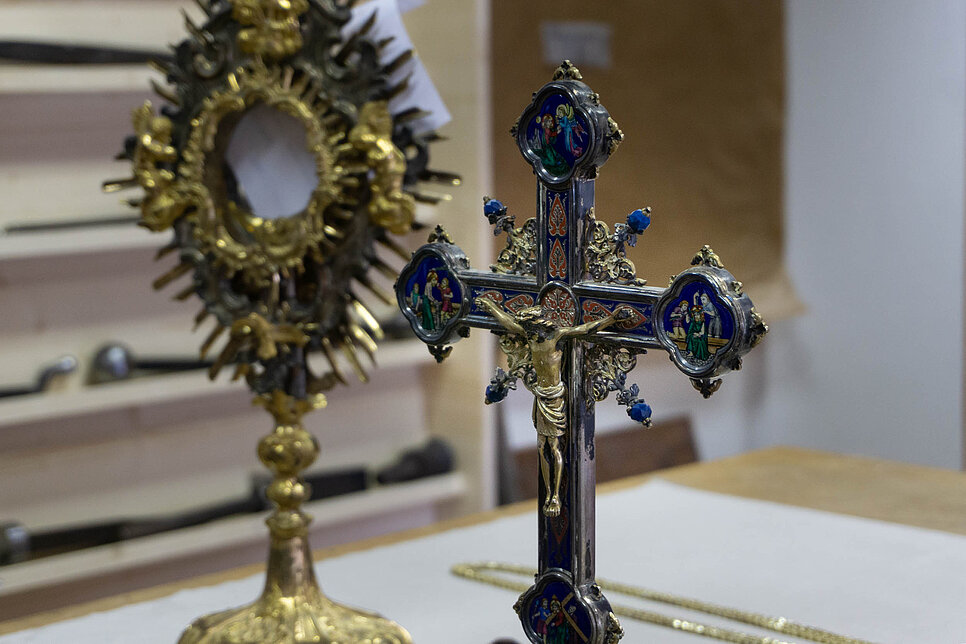 Monstranz und Kreuz aus Gold stehen auf einem Tisch