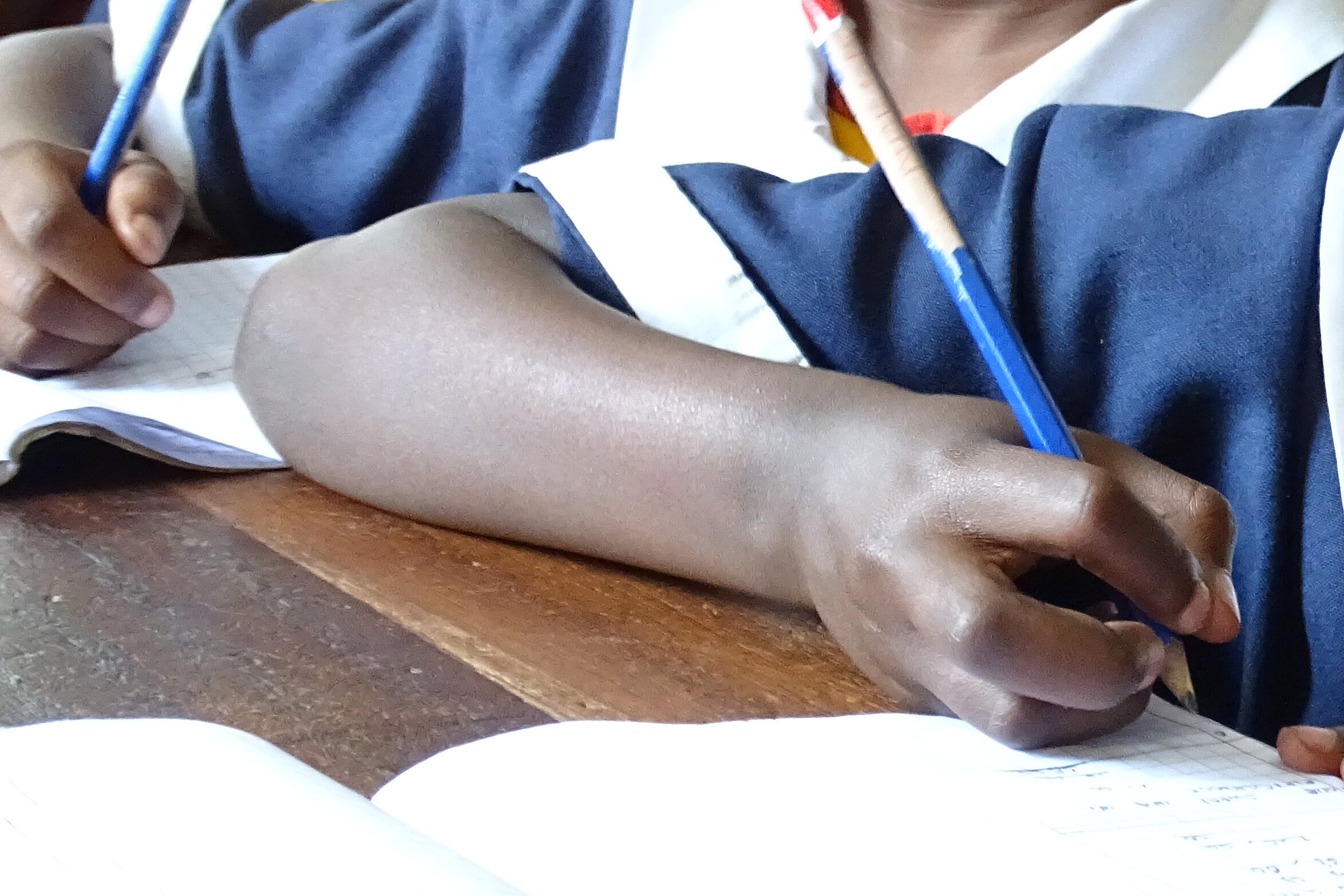 Drei Kinder sitzen an einem Tisch und zeichnen mit Buntstiften.