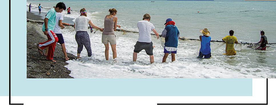 Menschen am Strand beim Lerneinsatz, die ein Seil halten.