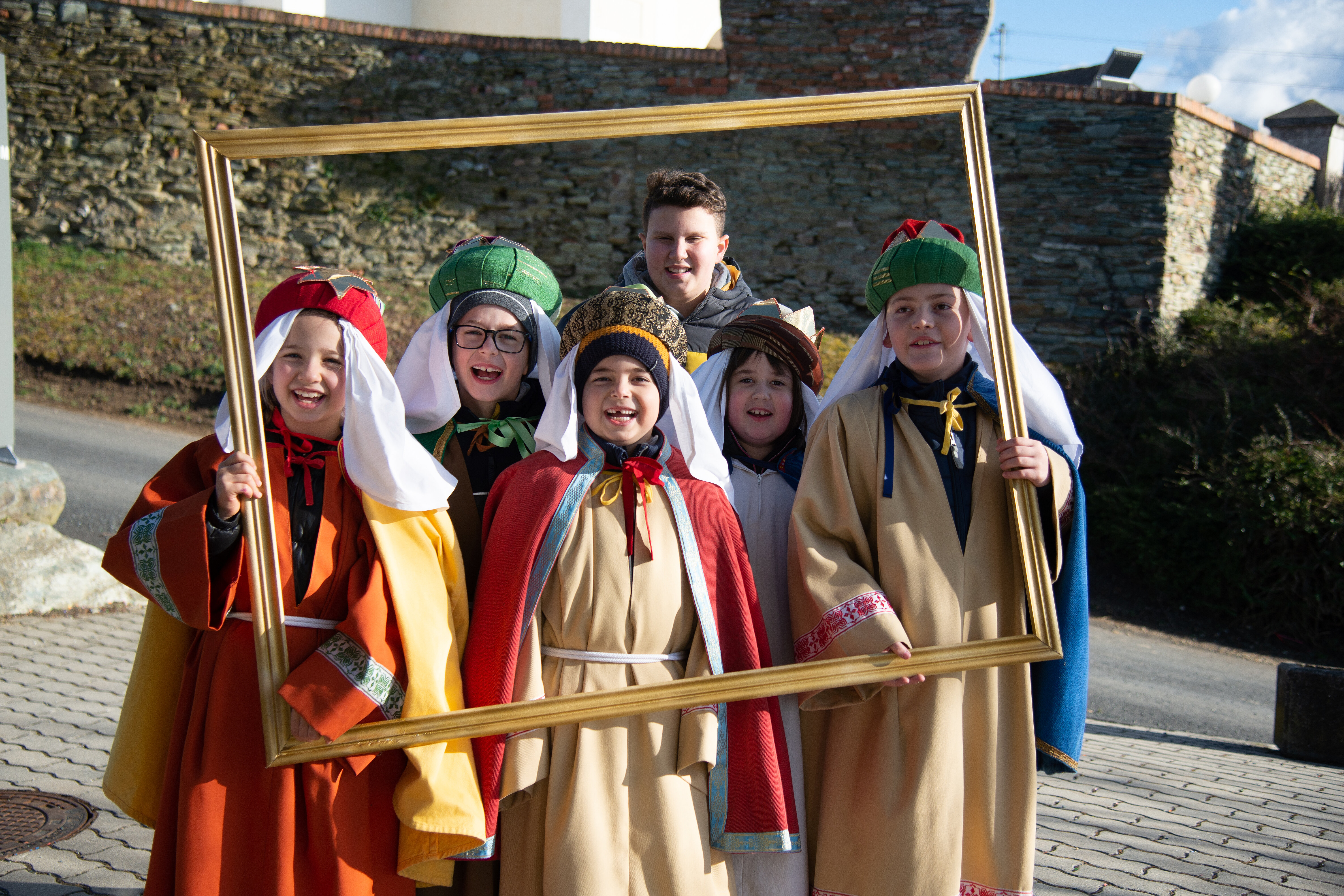 Kinder im Königsgewand blicken durch einen goldenen Rahmen in die Kamera.